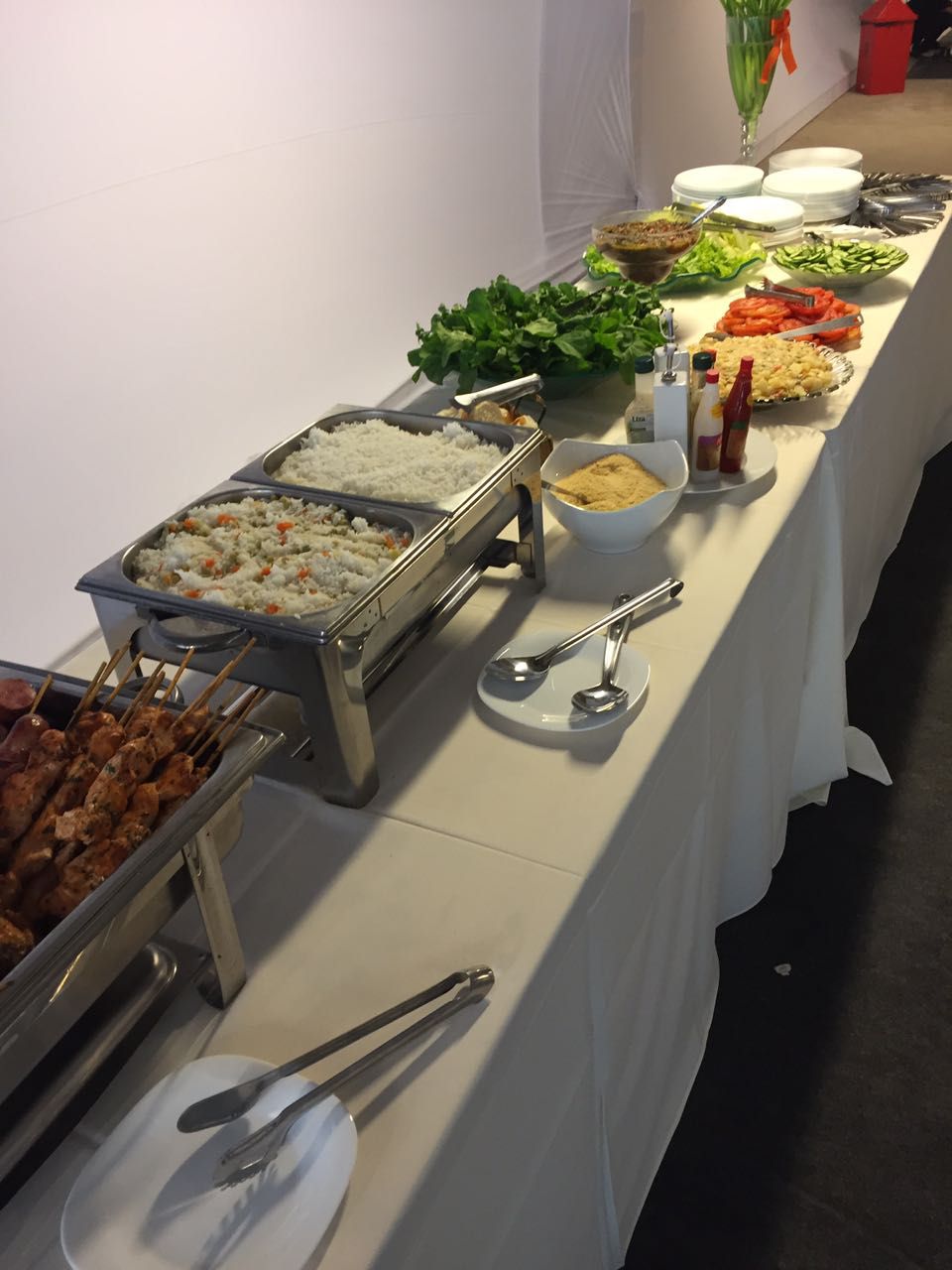 Linha de buffet com espetinhos de churrasco, arroz e saladas