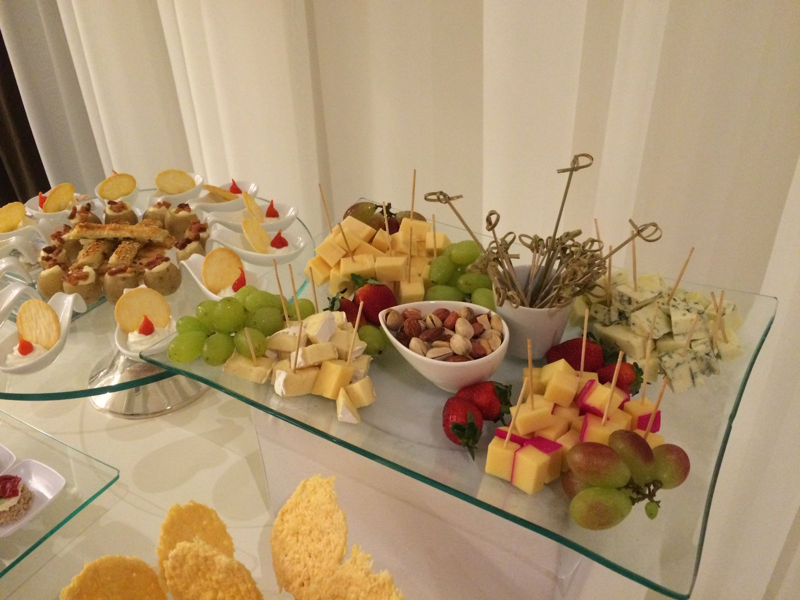 Mesa de queijos finos com uvas, nozes e frios em vidro