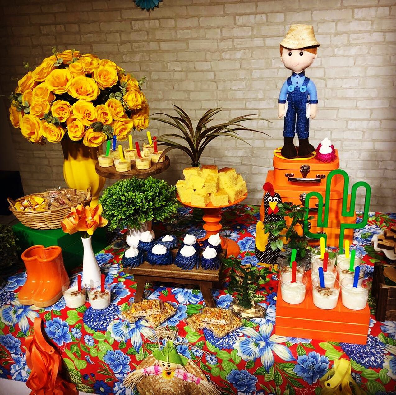 Mesa de doces juninos com rosas amarelas e decoração de fazendinha