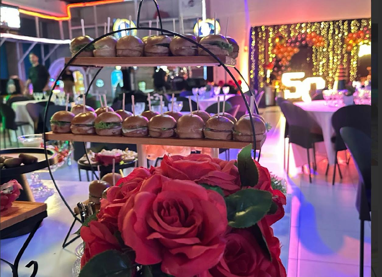 Festa de 50 anos com rosas vermelhas, hambúrgueres e iluminação dourada