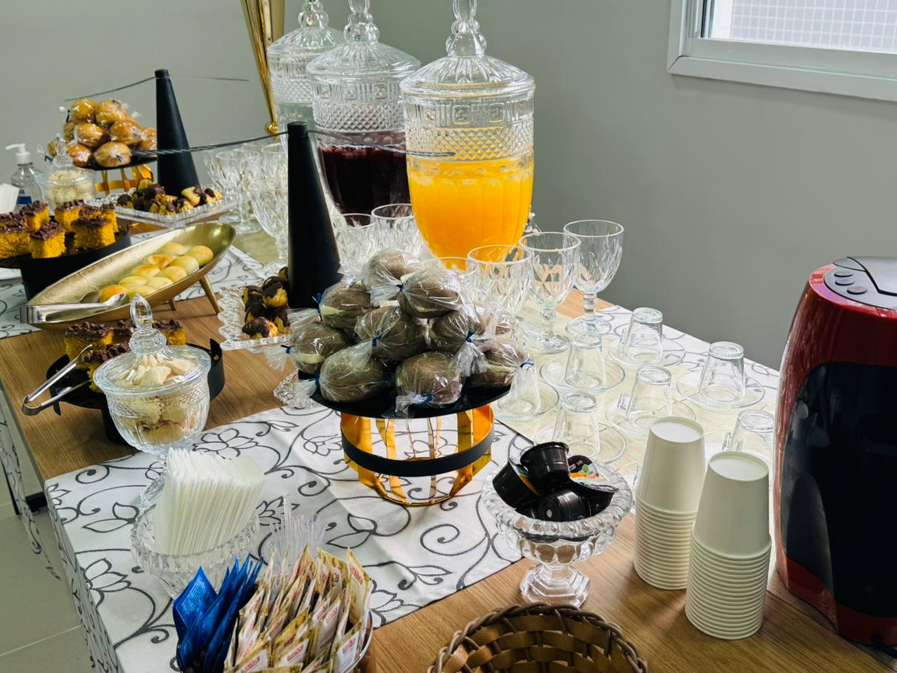 Mesa de doces com sucos em jarras de cristal e brigadeiros