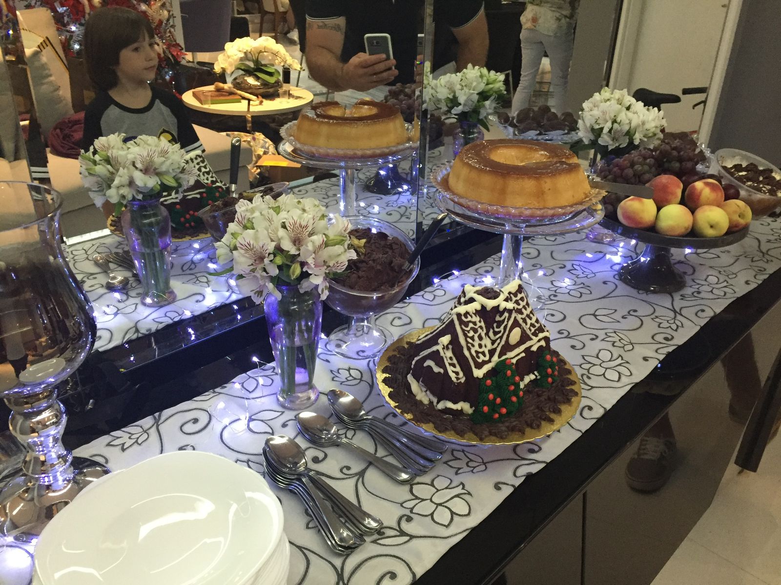 Mesa de doces elegante com pudim, casa de gengibre e luzes de fada